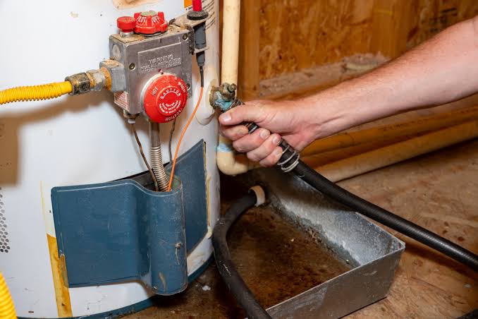 a technician draining sediment and water through the bottom valve
