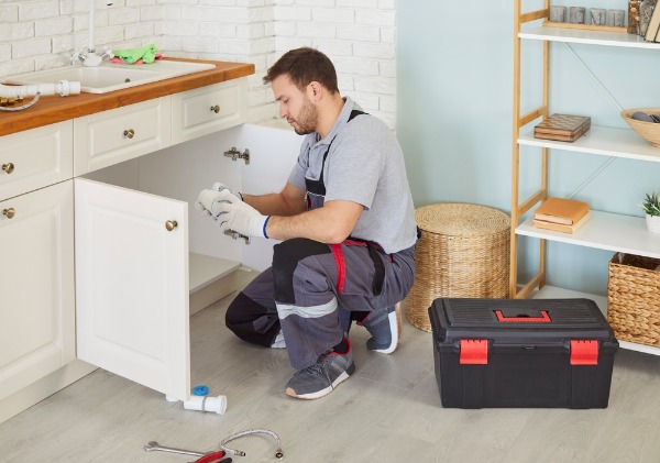 plumber repairing kitchen sink drain pipe